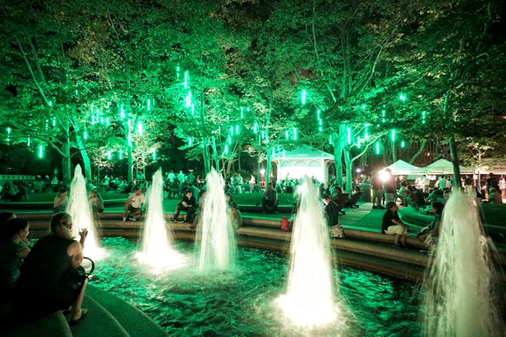 Plaza fountain lit with green lights at night