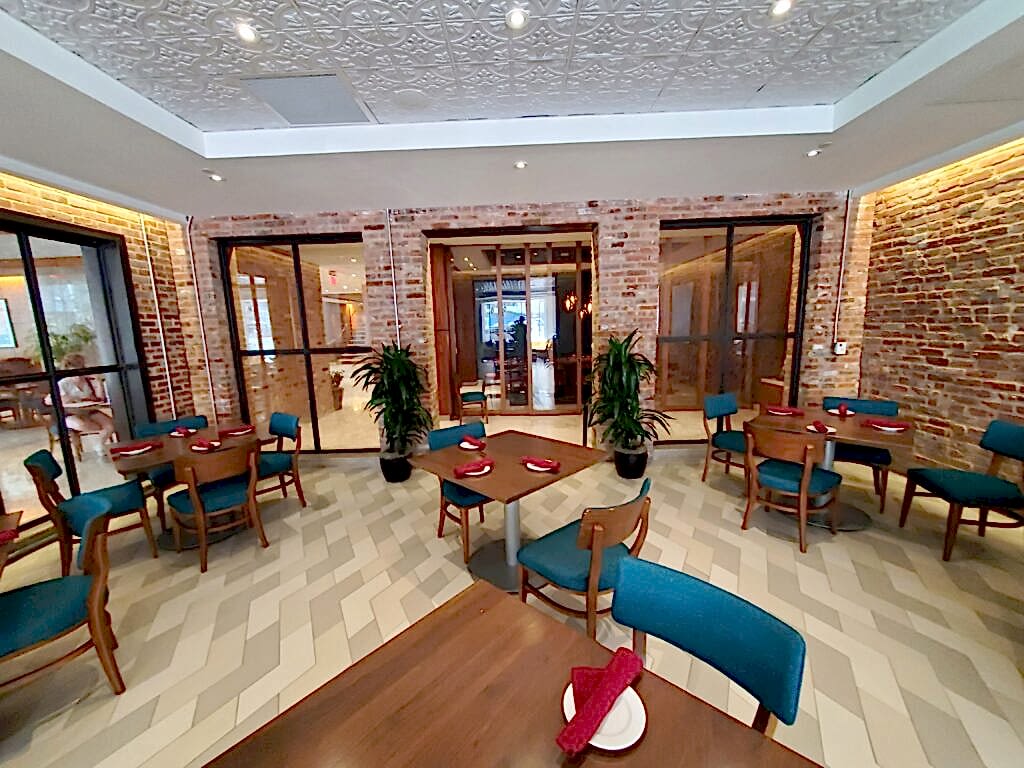 Potted plants in a commercial dining room with brick walls and teal chairs
